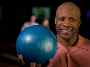 Smiling mature man holding bowling ball. Photo: db2stock