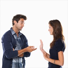 Studio shot of young couple having argument and gesturing. Photo: momentimages
