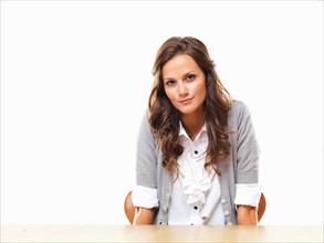 Portrait of attractive business woman sitting with hands under table. Photo: momentimages