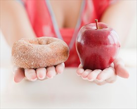 Close up of woman's hands holding donut and apple. Photo: Jamie Grill