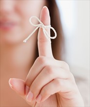 Close up of woman's finger with tied knot. Photo : Jamie Grill