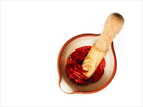 Studio shot of Mortar and Pestle with Red Chili Peppers on white background. Photo: David Arky