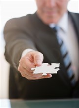 Close up of Businessman holding jigsaw piece. Photo : Jamie Grill