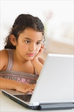 Girl (8-9) using laptop.