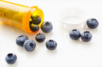 Blueberries spilling from prescription bottle.
