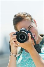 Portrait of young woman taking pictures with camera.