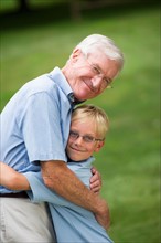 Grandfather and grandson (10-11) embracing.