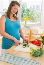 Young pregnant woman preparing food.
