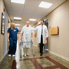 Senior man in hospital walking with walker.