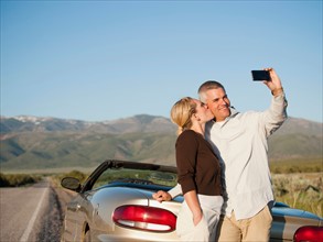 USA, Utah, Kanosh, Mid adult couple photographing themselves in front of majestic mountain range.