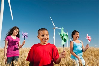 USA, Oregon, Wasco, Pre-teen girls (10-11) and boy (8-9) holding fans in wheat field in front of