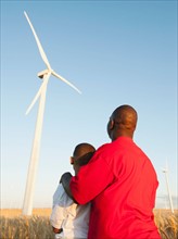 USA, Oregon, Wasco, Father and son (8-9) standing in wheat field, watching wind turbine.