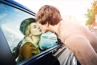Young couple kissing through window of car. Photo: Take A Pix Media