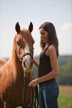 Young woman with horse in field. Photo: Jan Scherders