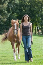 Portrait of young woman with horse in field. Photo : Jan Scherders