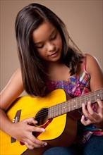Studio shot of girl (10-11) playing guitar. Photo : Rob Lewine