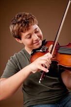 Studio shot of boy (12-13) playing violin. Photo: Rob Lewine
