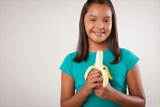 Studio portrait of girl (10-11) holding banana. Photo : Rob Lewine