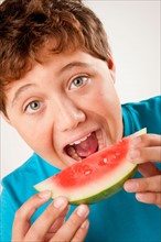 Studio portrait of boy (12-13) eating watermelon. Photo : Rob Lewine
