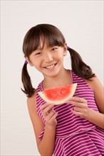 Studio portrait of girl (10-11) eating watermelon. Photo : Rob Lewine