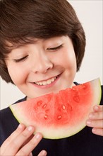 Studio portrait of boy (10-11) eating watermelon. Photo : Rob Lewine