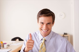 Portrait of businessman with thumbs up. Photo : Rob Lewine