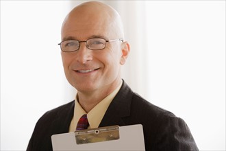 Portrait of business man holding clipboard. Photo: Rob Lewine