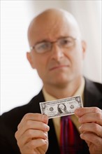 Portrait of business man holding one dollar bill. Photo : Rob Lewine