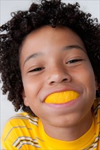 Studio portrait of boy (8-9) with slice of lemon in mouth. Photo : Rob Lewine