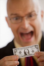 Portrait of business man holding one dollar bill. Photo: Rob Lewine