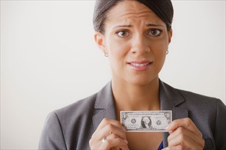 Studio shot of business woman holding small one dollar bill. Photo : Rob Lewine