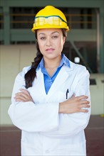 Portrait of woman wearing lab coat and hardhat. Photo: db2stock