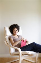 Portrait of young woman sitting in armchair. Photo : Rob Lewine