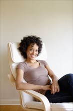 Portrait of young woman sitting in armchair. Photo : Rob Lewine