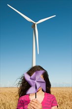 USA, Oregon, Wasco, Girl (12-13) holding fan n front of wind turbines.