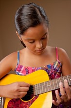 Studio shot of girl (10-11) playing guitar. Photo : Rob Lewine