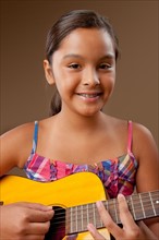 Studio portrait of girl (10-11) playing guitar. Photo : Rob Lewine