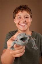 Studio portrait of boy (12-13) holding plastic animal. Photo: Rob Lewine