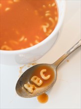 Close up of soup with letter noodles on spoon . Photo : Jamie Grill