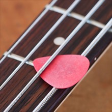 Close-up of bass guitar with guitar pick. Photo : Daniel Grill