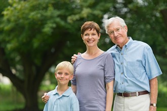 Three generation family standing in park.