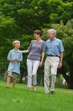 Three generation family walking in park.