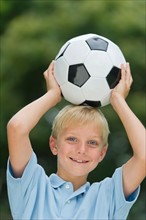 Boy (10-11) holding soccer ball.
