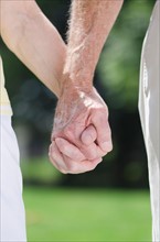 Senior couple holding hands, close-up.