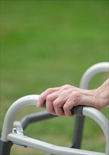 Senior walking with walker, close-up of hands.