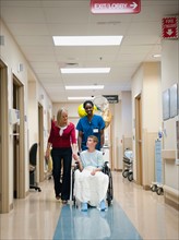 Nurse and mother walking behind boy's (10-11) wheelchair.