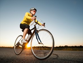 Mid adult woman cycling on empty road.