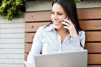 Portrait of young businesswoman sitting on bench using laptop. Photo: Take A Pix Media