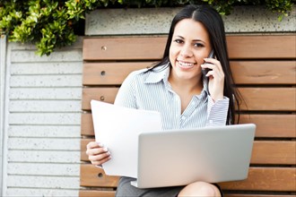 Portrait of young businesswoman sitting on bench using laptop. Photo: Take A Pix Media