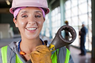 Portrait of female manual worker wearing hardhat holding tool. Photo: db2stock
